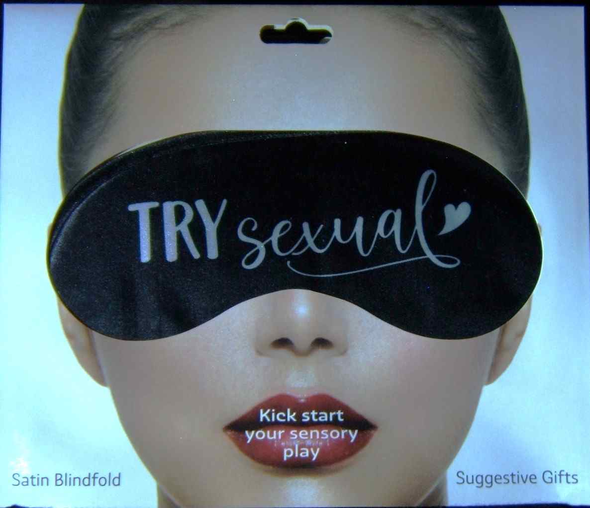 A woman wearing a black eye mask with the words " try sexual ".