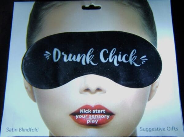 A woman wearing a black eye mask with the words drunk chick written on it.