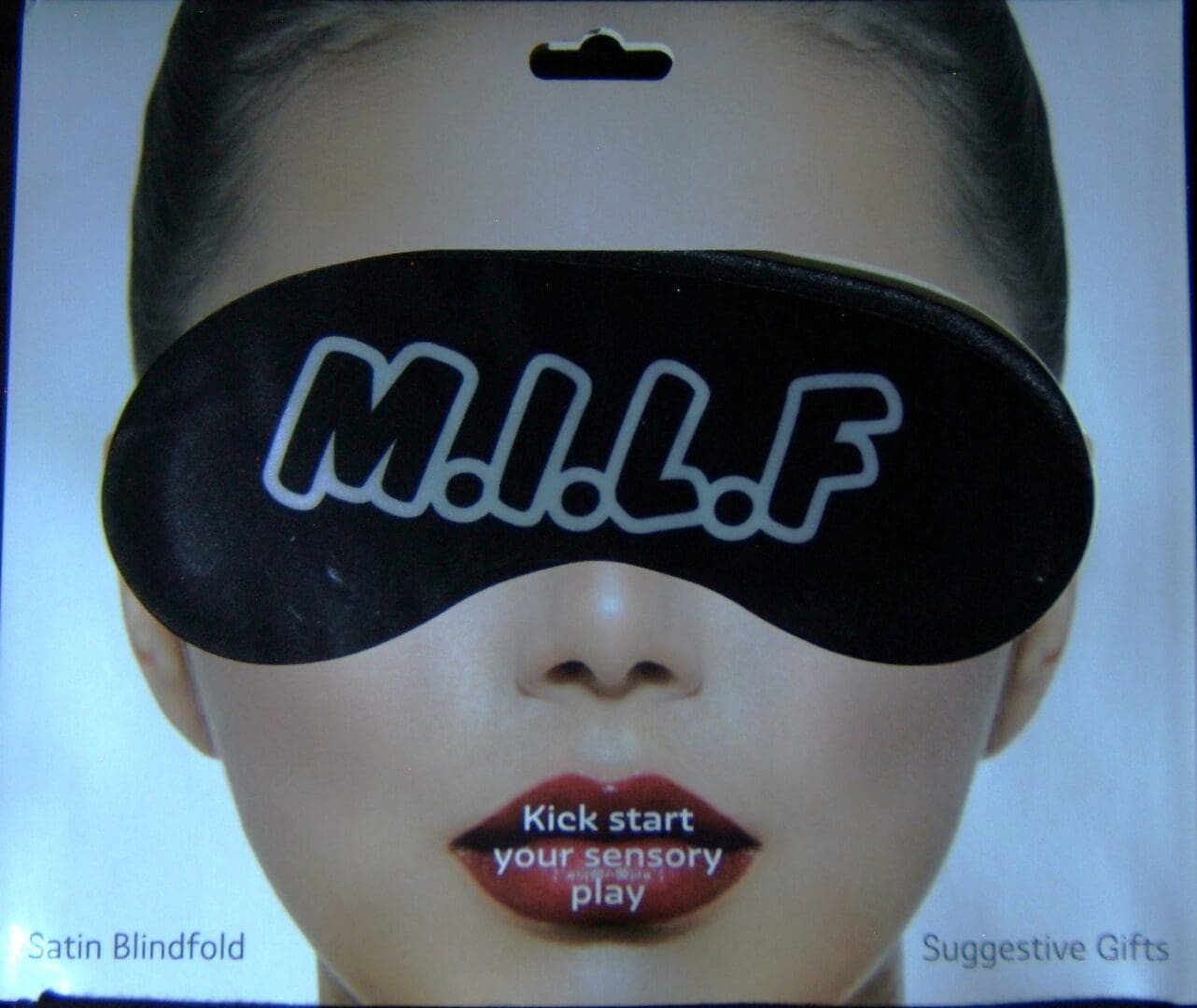 A woman wearing a black eye mask with the word " milf " written on it.